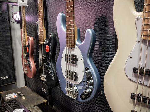 Lynnwood, WA USA - circa May 2022: Selective focus on electric and acoustic bass guitars for sale inside a Guitar Center musical instrument store.