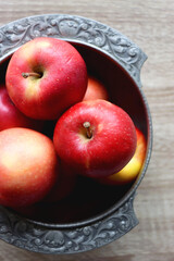 Silver bowl full of red apples on wooden table. Top view.