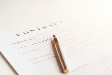 The pen is on the contract and the contract is on a white background. Toned photo