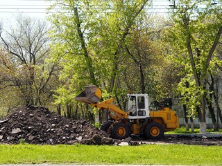 A truck loader is working on the construction of a new sidewalk. The use of technology in the improvement of the city.