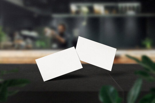 Clean minimal business card mockup on black top table in cafe with leaves