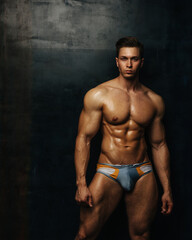 Fototapeta na wymiar Handsome fitness male model in swimwear posing in studio
