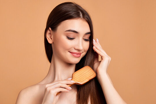 Beautiful woman combs her hair with wooden brush