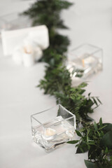 Decor of candles and green flowers on the wedding table in the restaurant.
