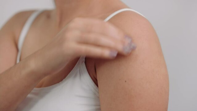 Close on young model rubbing shoulder and neck to relieve pain and sore muscles