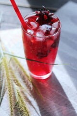 roselle juice in a glass, placed on a white table.
