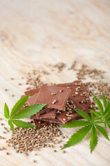 Vegan Chocolate with cannabis leaves and seeds on wooden background. Healthy take of break