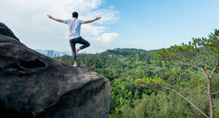 Young man doing yoga on mountain peak