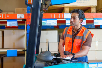 Man warehouse worker in the forklift checking the daily order in warehouse. Warehouse and Logistic business concept.