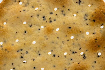 A Macro shot of a cracker with salt and seeds. The texture of a biscuit cracker