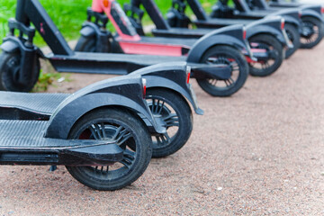 Wheels of electric red and black scooters close-up. Car sharing of light transport along the streets of St. Petersburg and Russian cities. Companies that provide transport for rent for movement.