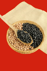 Black beans spoon on the brazilian beans in red background.