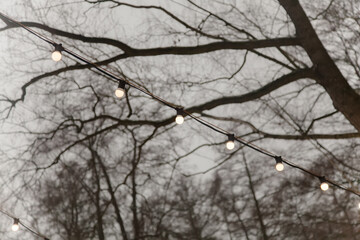 Small garland lights hang over the summer cafe.Street lighting in parks and squares. Christmas decoration of restaurants and buildings. Festive decor.