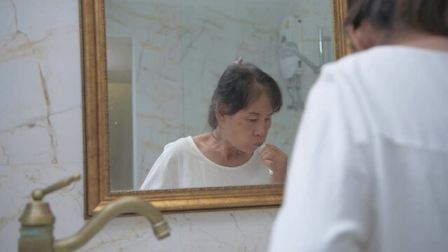 Health concept of 4k Resolution. Asian old woman brushing teeth in the bathroom.