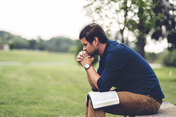 Caucasian male sitting and praying in the park