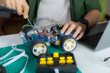 An Asian boy is building a metal robot