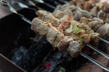 Marinaded pork meat pieces on skewers frying over bonfire. Kebab or traditional shashlik cooking with lot of smoke.