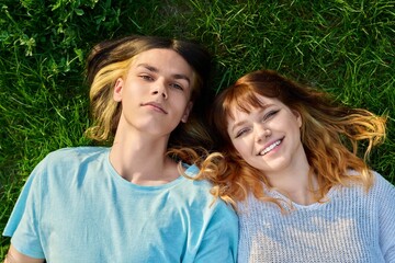 Naklejka premium Couple of teenagers friends looking at camera on green grass background.