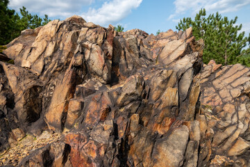 Huge rock formations surrounded by trees under a blue cloudy sky on a sunny day in Sudbury, Ontario