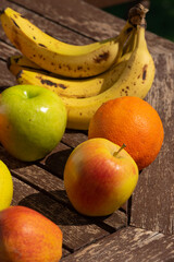 Manzanas, platanos y naranjas sobre mesa de madera