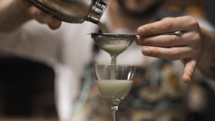 Experienced bartender filters sludge and pours cocktail drink