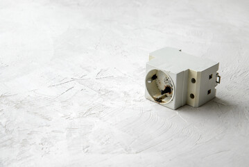 Unusable electrical socket after short circuit and fire, gray concrete background, copy space.