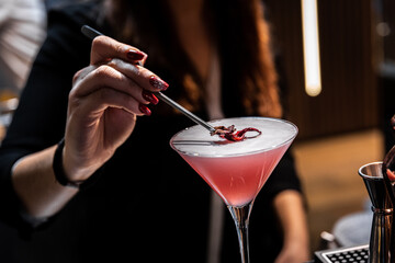Special pink cocktail with flower petal on top served by a barista