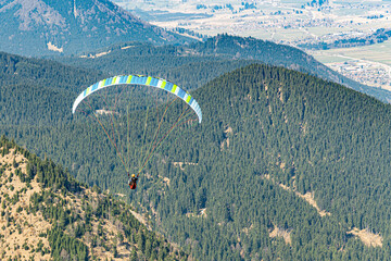 Man paragliding in the air between high mountains.