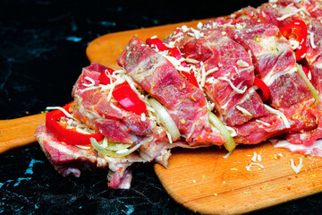 Loin meat with spices, cut into pieces, lies on a cutting board for further cooking on a fire or in the oven.