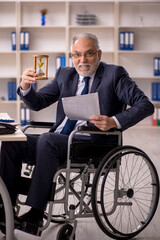 Old male employee in wheel-chair in time management concept