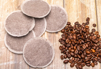 Top view of coffee pads and coffee beans on a rustic wooden surface as an example of various coffee...
