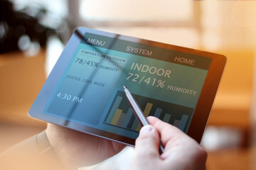 Man is Adjusting a  temperature using a tablet with smart home app