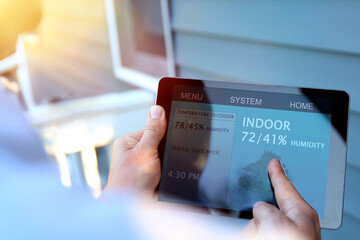 Man is Adjusting a  temperature using a tablet with smart home app