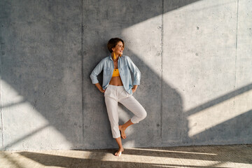 smiling happy beautiful woman posing against concrete wall on sunny day summer fashion style trend