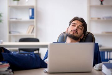 Young male employee extremely tired in the office
