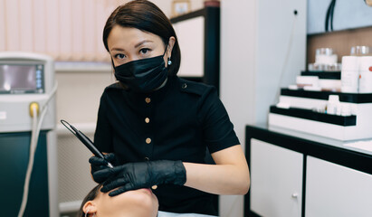 Beautician do eyebrow microblading of asian girl