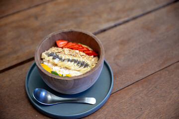 Mango smoothies bowl with berries, granola, chia seeds and coconut on concrete background
