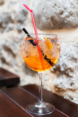 Glass of aperol on a wooden table in outdoor cafe. Vacation and celebration concept. Close-up. Selective focus.