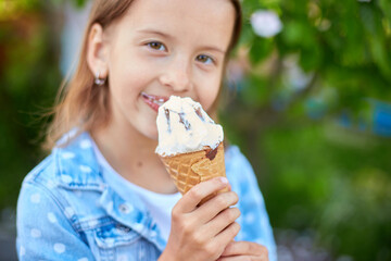 Cute girl with italian ice cream cone smiling and looking at camera while resting in park on summer day