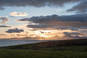 Obraz premium Fabulous sunset near Kilberry village in Argyll and Bute, with crepuscular rays piercing through the heavy dark clouds, beautiful twilight over one of the most remote parts of the Scottish Highlands