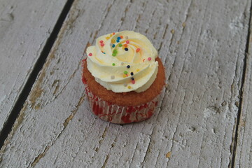 Sweet cake with tutti frutti sprinkles on top on the wooden table white background.