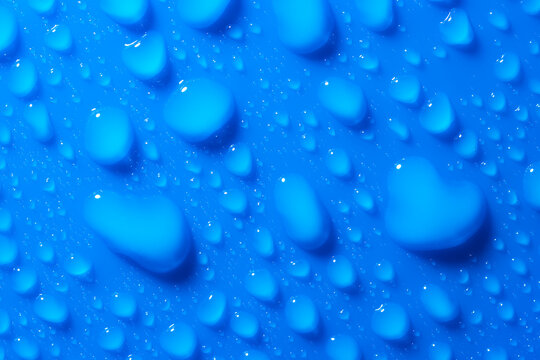 Macro shot of drops of water on a blue flat surface. Abstract blue background