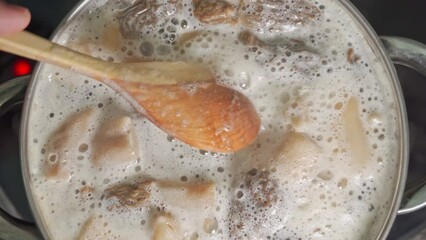 The cook is stirring morel mushrooms cooked in a saucepan with a wooden spoon - Powered by Adobe