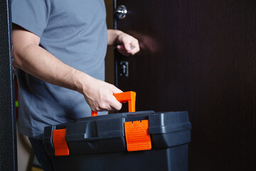 Man with a suitcase of tools coming in client home. Repairman or husband on hour service, hands holding a toolbox.