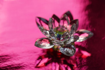 Crystal lotus on red table with light reflection. Muladhara chakra symbol.