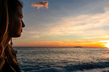 Fototapeta premium Happy woman enjoying sunset from Marina Grande beach in Positano at Amalfi Coast, Italy, Campania, Europe. Selective focus on person face. Sun going down behind Li Galli islands in Mediterranean Sea
