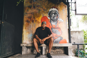 Portrait of happy African American hipster guy dressed in casual clothes smiling at camera while...