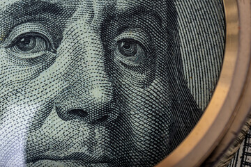 Close-up portrait of Ben Franklin on the US 100 dollar bill under a magnifying glass. Benjamin Franklin on one hundred dollar American banknote, close-up