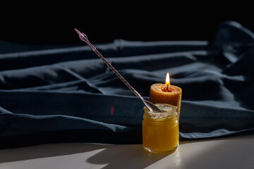 A jar of honey about a teaspoon on a blue tablecloth