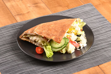 Doner kebab on a dark plate.